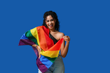 Happy African-American woman with rainbow flag on blue background. LGBT concept