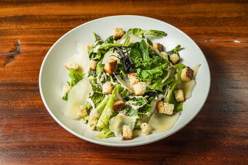 Exquisite chicken caesar salad on wooden table. Hotel restaurant food. Gastronomy.