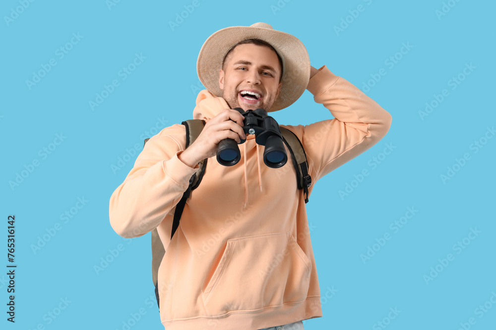 Wall mural male tourist with backpack and binoculars on blue background