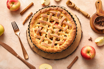 Tasty homemade apple pie with fruits, cinnamon and cutlery on beige grunge background