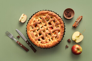 Tasty homemade apple pie with fruits, cinnamon and cutlery on green background