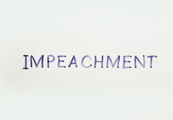 Word IMPEACH written with felt pen on glass against white background