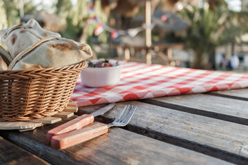 Chilean pino empanadas, wicker basket, and wooden table in park, with a bowl of pebre, kitchen...