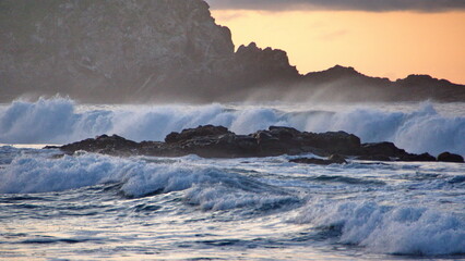 Waves breaking around rocks just off the beach, at sunrise, in Zipolite, Mexico