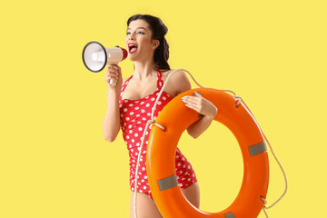 Beautiful pin-up lifeguard with ring buoy shouting into megaphone on yellow background