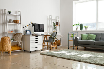 Interior of light office with workplace, sofa and shelving units