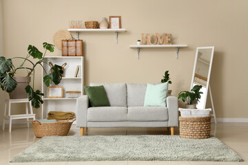 Light interior of comfortable living room with sofa, houseplants and shelving unit