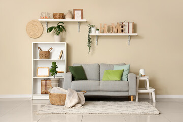 Modern interior of comfortable living room with cozy sofa, carpet and shelving unit