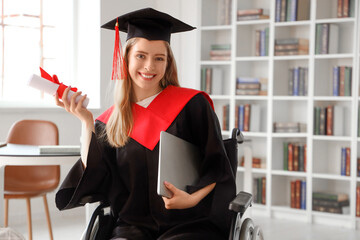 Female graduate in wheelchair with laptop and diploma at university