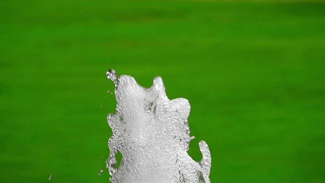 Slow-motion artesian fountain on green background
