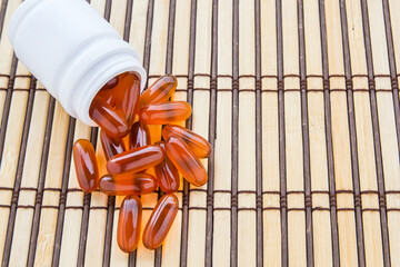 Fish oil capsules on bamboo mat background