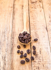 Coffee beans in wooden spoon on wooden background