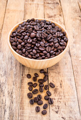 Coffee beans in wooden bowl on wooden background