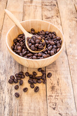 Coffee beans in wooden bowl on wooden background