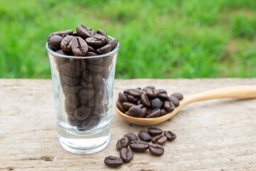 Coffee beans in glass on wooden background