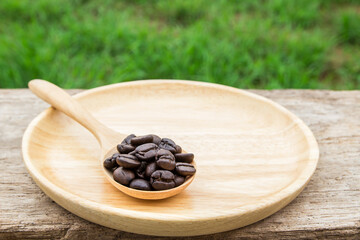 Coffee beans in wooden spoon on wooden background