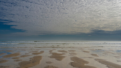 The low tide in the ocean. Rivulets of water form a bizarre pattern on the sand. Turquoise waves...