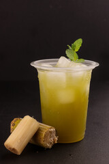 Es Tebu or Fresh Squeezed Sugar Cane Juice with Fresh Sugar Cane on Plastic Cup.