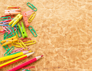 Colorful pencil and paperclips on old paper background