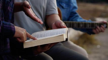 Three men read,pray and studied the bible at the park and prayed together. sharing the gospel with...
