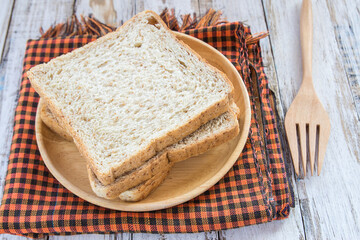 Whole wheat bread on wooden plate - obrazy, fototapety, plakaty