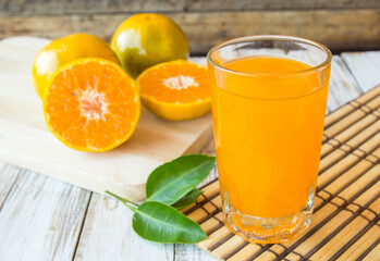Obraz na płótnie Canvas Glass of freshly pressed orange juice with sliced orange on wooden table
