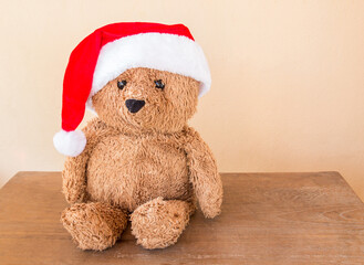 Teddy bear wearing a christmas hat on wooden table