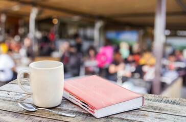Notebook and coffee cup on wooden table with blurred coffee shop