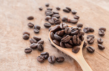 Coffee beans in wooden spoon on wooden background