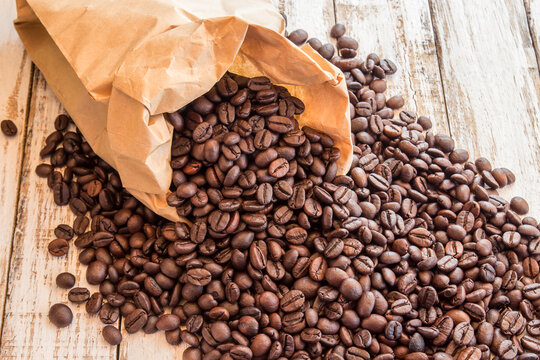 Black coffee beans in paper bag on wooden table