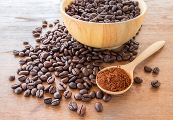 Coffee powder in wooden spoon and coffee beans on wooden table