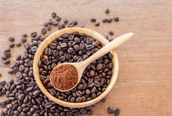 Coffee powder in wooden spoon and coffee beans on wooden table