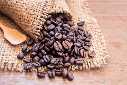 Black coffee beans in burlap sack on wooden table
