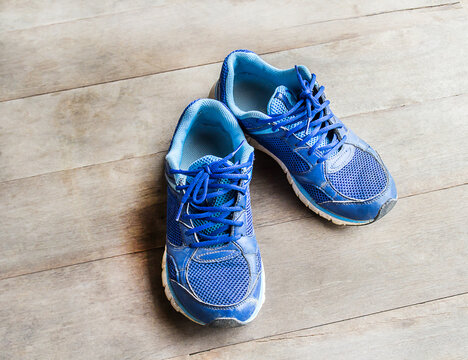blue running shoes laid on a wooden floor