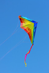 Rainbow-colored kite flying in a clear blue sky