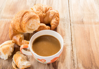 Coffee and croissant for breakfast on wooden table
