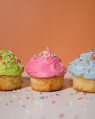 Closeup of a pink blue and green cupcakes with colourful sprinkles