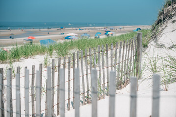 Wooden fence overlooking beach with dunes and beach umbrellas