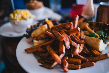 Close-up of restaurant meal with sweet potato fries and sandwich
