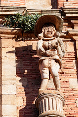 Human gargoyle laughing and filling a bowl of wine