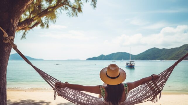 A rear view of a female traveler in a straw hat relaxing in a hammock on the beach of the Sea. Summer Holidays, Travel, Landscape concepts. Horizontal photo, copy space