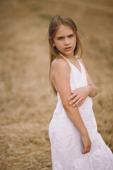Fototapeta na wymiar Beautiful blonde girl in summer dress posing on the field