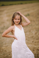 Fototapeta na wymiar Adorable blonde girl in summer dress posing on the field
