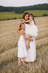 Fototapeta na wymiar Happy mother and her daughters in summer dresses embracing