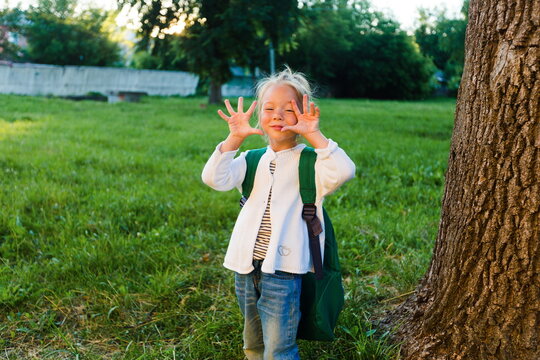 A little girl makes faces and has fun in a beautiful summer park.