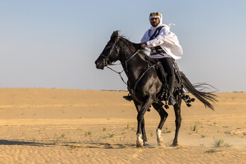 Arabian horseback archer riding his stallion in the middle of sand dunes