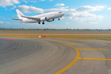 View of the turn from the taxiway onto the runway and a passenger jet plane taking off against the background