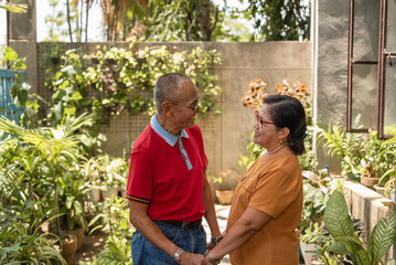 Loving elderly Asian couple holding hands in a lush garden