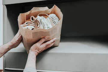 Man depositing clothes in clothing donation containers for public drop off.