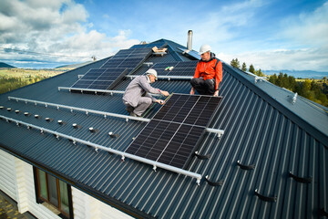Male technicians adjusting the solar panel on roof of house. Solar system installation on top of...